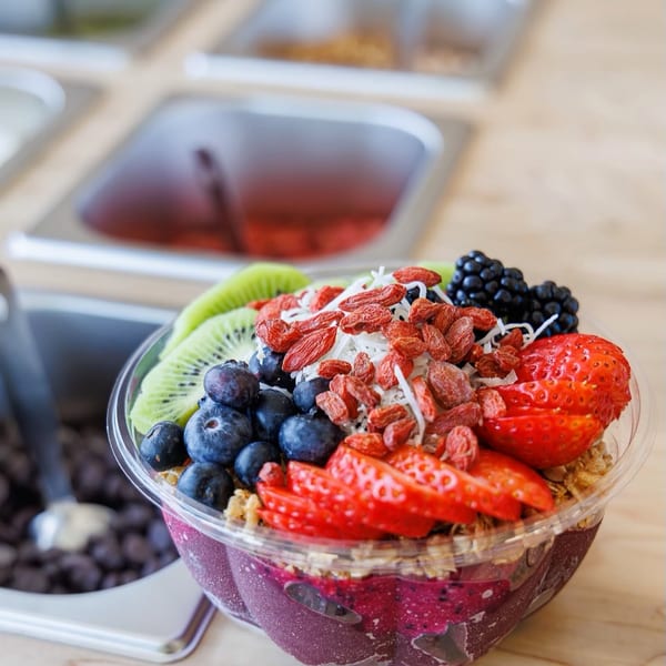 A vibrant acai bowl topped with kiwi, blueberries, strawberries, goji berries, and coconut flakes.