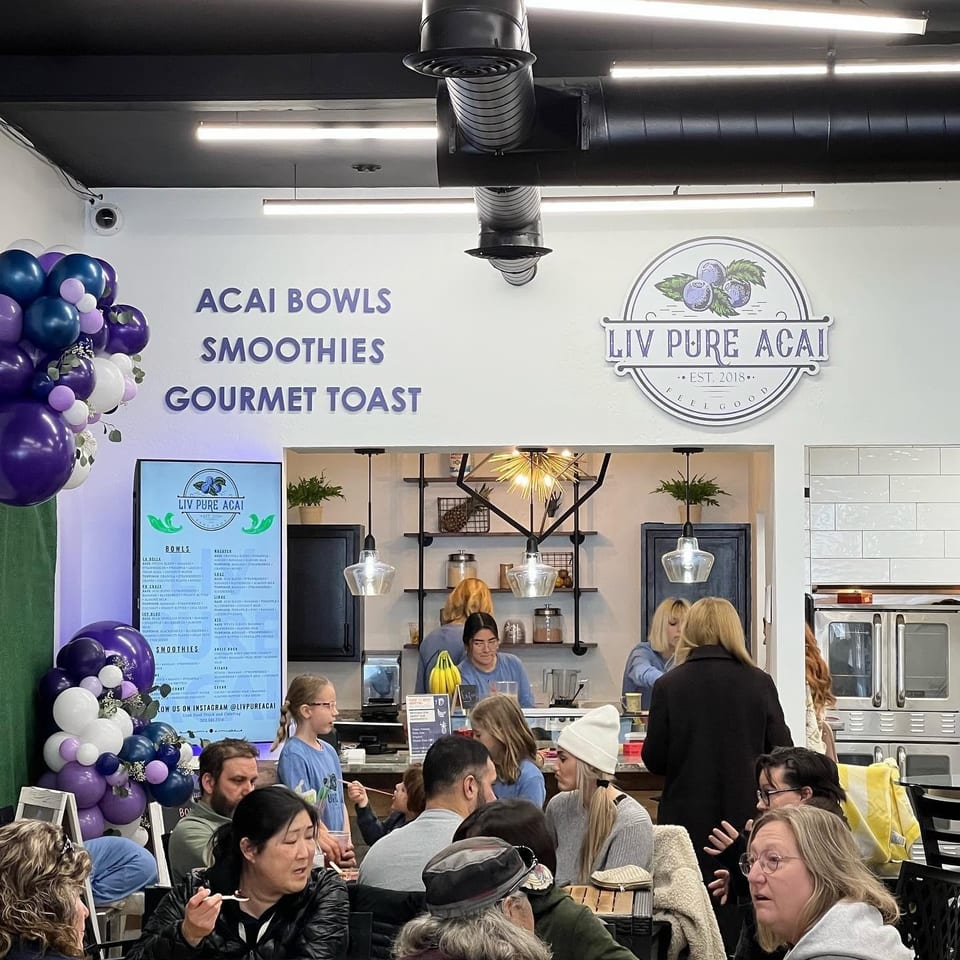 Customers enjoying acai bowls and smoothies inside Liv Pure Acai, a bright and modern cafe.