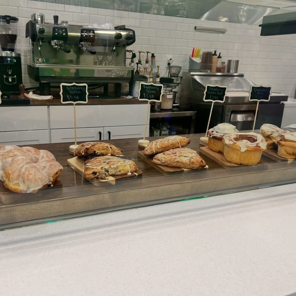 A bakery display case with glazed twists, blueberry scones, raspberry scones, and cinnamon rolls.